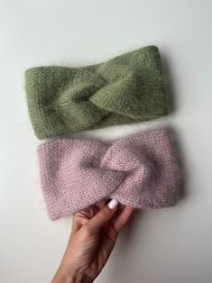 three different colored knitted headbands with one being held up to the side