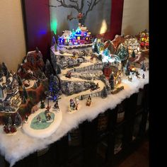 a christmas village is displayed on top of a table in front of a large painting