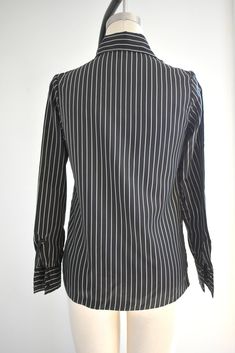 "Description: 1970s black and white striped silky polyester blouse. Long sleeves with pleated shoulders. Button front. Condition: In great condition, with no holes or stains. Designer: It's Gailord Stated Size: 10 Measurements: Armpit to armpit: 18\" Shoulder to shoulder: 14.5\" Sleeve length: 23\" Overall length: 23\" Waist: up to 35\" ---> If you need an order shipped by a particular date or shipped via a quicker method, please ask PRIOR to purchase to see if we can accommodate that request Fitted Black Top With Vertical Stripes, Elegant Fall Blouse With Striped Collar, Formal Striped Tops With Button Closure, Chic Formal Blouse With Vertical Stripes, Elegant Striped Shirt For Office Wear, Elegant Striped Fall Blouse, Elegant Office Blouse With Vertical Stripes, Elegant Striped Blouse For Fall, Pinstripe Button-up Blouse For Work