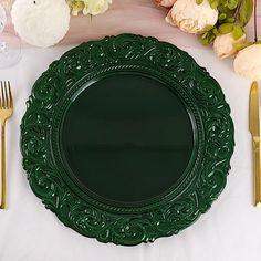 a green plate sitting on top of a table next to gold forks and knifes