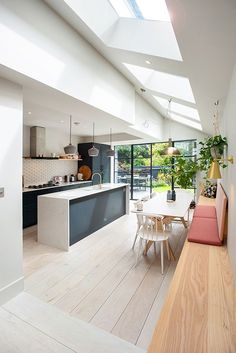 an open kitchen and dining room area with skylights above the counter, along with white walls and wooden flooring