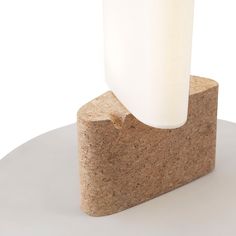 a white vase sitting on top of a block of cement next to a light bulb