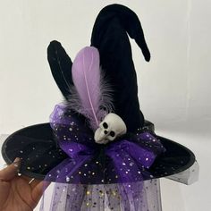 a hand holding a purple hat with a skull on it