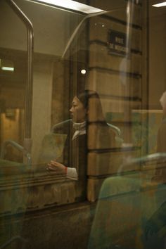 a woman sitting on a train looking out the window at another person standing next to her