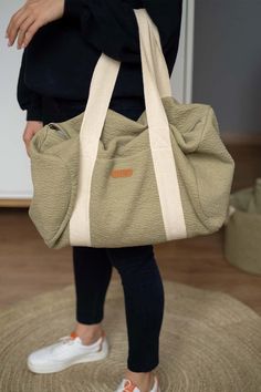 a woman carrying a beige bag on top of a rug