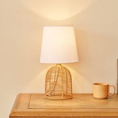 a wooden table with a lamp on top of it and a cup next to it