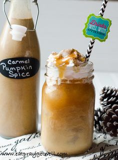 two mason jars filled with pumpkin spice and topped with whipped cream, caramel syrup, and a pine cone