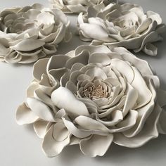 three large white flowers sitting on top of a table