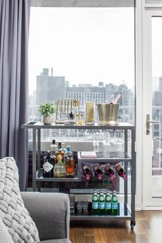 a living room filled with furniture and lots of bottles on top of a metal shelf