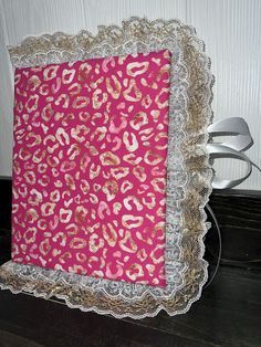 a pink and gold leopard print with white lace on the edge is sitting on a black table