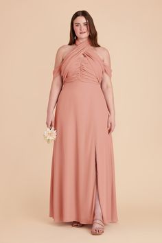 a woman in a long pink dress is standing with her hands on her hips and looking at the camera