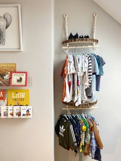 there is a rack with clothes and books on the wall next to a book shelf