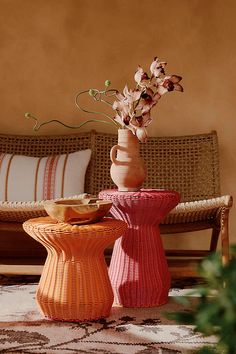 two vases with flowers in them sitting on a table next to a couch and pillows