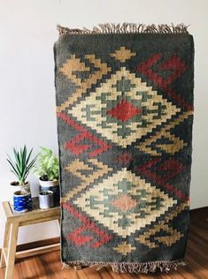 an old rug is sitting on the floor next to a potted plant in a room