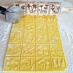 a cookie sheet with flowers on it next to a rolling pin