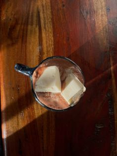 two pieces of cheese sitting in a glass on top of a wooden table