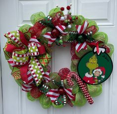 a christmas wreath with grin the grin on it and candy canes hanging from the front door