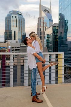 a man and woman kissing on the roof of a building with skyscrapers in the background