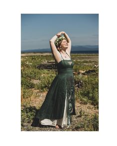 a woman in a green dress is standing on the ground with her hands behind her head