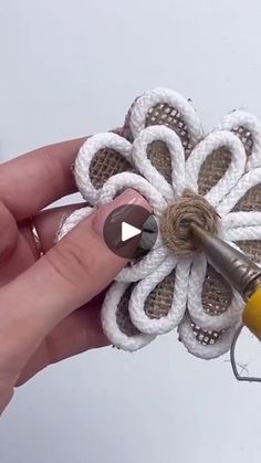 someone is holding a crocheted flower with scissors