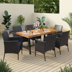 an outdoor table and chairs on a deck with potted plants in the back ground