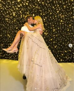 a man and woman are kissing in front of a backdrop with stars on the wall