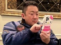 a man holding up a hello kitty cell phone