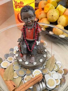 a small statue sitting on top of a glass plate filled with coins and other items