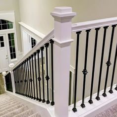 a white staircase with black handrails and carpet on the floor next to it