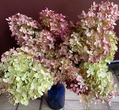 a blue vase filled with pink and green flowers