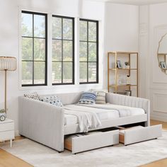 a day bed with pull out drawers in front of two windows and a rug on the floor