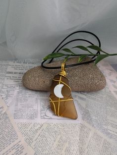 This wire wrapped sea glass necklace is made of glass found on the beaches of Newfoundland. It is also made on an 18" black wax cord necklace with a 2" extension chain for easily adjusting the size of your necklace. It comes with a beautiful mother of pearl moon bead attached. BROWN SEA GLASS MEANING: Brown is the color of earth, home and foundations. It encourages stability, approachability and comfort. Brown is deeply tied to all things natural and organic, and a feeling of wholeness and groun Adjustable Wire Wrapped Necklaces In Recycled Glass, Adjustable Wire Wrapped Necklace In Recycled Glass, Wax Cord Necklace, Brown Sea, Beautiful Moon, Sea Glass Necklace, Beach Glass, Cord Necklace, Newfoundland