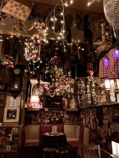 a room filled with lots of hanging lights and pictures on the wall next to a table