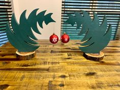 two wooden christmas trees with ornaments in the shape of birds on them sitting on a table