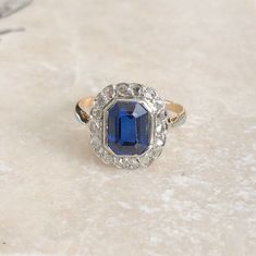 An Art Deco 18 carat gold and platinum blue stone and Diamond ring. This beautiful piece holds a gorgeous collection of rose cut diamonds and a deep blue stone right in the centre. Elegant and classic! CONDITION: Wear consistent with age and use. Please see photos for more detail. APPROX. SETTING SIZE: 11mm x 13mm APPROX. SETTING HEIGHT: 6mm APPROX. BAND WIDTH: 1mm RING SIZE: UK: M | US: 6 1/4 WEIGHT: 3.0 grams Blue Art Deco Rings With Cabochon, Art Deco Brilliant Cut Sapphire Ring Gift, Art Deco Blue Cabochon Rings, Art Deco Multi-stone Oval Sapphire Ring, Luxury Art Deco Multi-stone Sapphire Ring, Blue Stone Ring, Rose Cut Diamond, Multi Stone, Multi Stone Ring