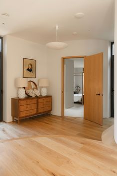 an empty room with wood floors and white walls, including a large mirror on the wall