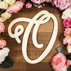 the letter f is surrounded by flowers and greenery on a wooden surface with pink and white peonies