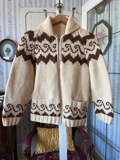 This hand knit Cowichan style sweater is made from beige wool accented with a unique rusty brown wave design. It has a full zipper in the front and two front pockets. The measurements, taken with the sweater lying flat, are: shoulder to shoulder, 16 inches; armpit to armpit, 18 inches; sleeves, 23 inches; length, 27 inches; bottom edge, 20 inches (with slightly stretchy ribbing). In very good condition. Cozy Brown Chunky Knit Sweater Coat, Vintage Knitted Brown Outerwear, Hand Knitted Brown Outerwear For Fall, Hand Knitted Brown Sweater For Winter, Brown Hand Knitted Winter Sweater, Cozy Brown Wool Sweater Coat, Hand Knitted Brown Winter Knitting Pattern, Nordic Style Brown Cardigan For Fall, Bohemian Chunky Knit Brown Sweater