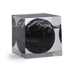 a black and white object sitting on top of a glass block in front of a white background