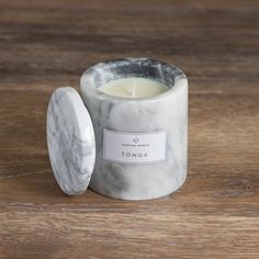 a marbled candle holder with a white label on the front and inside, sitting on a wooden surface