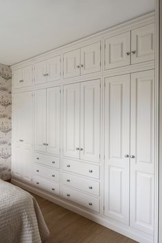 a bedroom with white cupboards and a bed