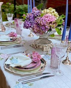 the table is set with pink and purple flowers