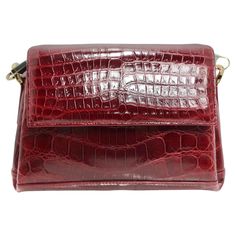 The BC Luxury Red Crocodile Leather Structured Handbag is a stunning accessory that exudes sophistication and elegance. Crafted from luxurious burgundy red crocodile leather, this structured mini handbag is sure to make a statement with its vibrant color and impeccable craftsmanship. The bag features a sleek and structured design with a magnetic foldover closure, providing easy access to your belongings while keeping them secure. The gold-tone stud feet at the bottom not only enhance the bag's a Structured Handbags, Cartier Earrings, Gucci Dress, Christian Louboutin Heels, Burgundy And Gold, Crocodile Leather, Crossbody Clutch, Mini Handbags, Women Clothing Boutique