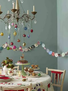 a table topped with a cake and plates covered in baubles next to a chandelier