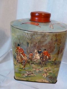 this is an old tin canister with horses and dogs on the front, along with other items