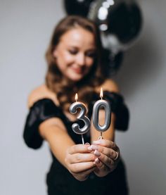 a woman holding a candle with the number 30 on it