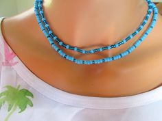 This blue seed bead choker necklace is made of two strands of turquoise and dark turquoise irredescent beads.  It is on a stretch cord so it is so easy to put on and take off.  the knot is covered with a beautiful silver sparkly crimp cover.  It is made with care on the top of the mountain in my chalet surrounded by fresh air.  The necklaces are made to last. One strand is 16 1/2" and the other is 17 1/4".  They come in a pretty gift box and ready to give. Turquoise Beads Choker As A Gift, Turquoise Beads Choker For Gift, Blue Turquoise Necklace With Spacer Beads As Gift, Handmade Blue Turquoise Choker Necklace, Adjustable Double Strand Turquoise Blue Necklace, Adjustable Double Strand Blue Turquoise Necklace, Blue Double Strand Beaded Necklace For Gift, Blue Double Strand Jewelry With Tiny Beads, Blue Seed Bead Necklace