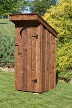 a wooden outhouse sitting on top of a lush green field