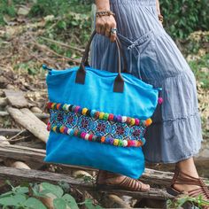 "The beautiful & unique tote bag with adorable colorful pom poms is made with an amazing piece of fabric woven by the HMONG hill tribes of Lanna Region (Northern Thailand). Easy to carry with strong leather strap, a zipper enclosure and inside pocket. We buy materials from Hmong market and we design and sew by hand. Some of the bags we modify to improve the product. The Hmong tribes live in the North of Thailand and have origins from the Tibetan area of China. N.B. YOU MAY NOT RECEIVE THE EX Blue Tote Hobo Bag For Festivals, Blue Tassel Bags For Daily Use, Blue Tote Shoulder Bag For Festivals, Blue Rectangular Bags For Festival, Bohemian Blue Hobo Tote Bag, Bohemian Turquoise Travel Bag, Bohemian Blue Shoulder Bag For Festivals, Blue Handwoven Festival Bag, Blue Shoulder Bag With Tassels For Daily Use