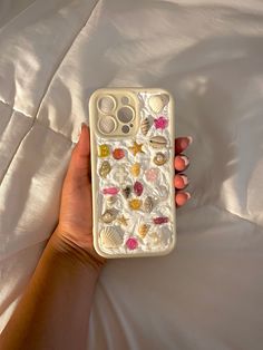 a woman's hand holding an iphone case with shells and seashells on it